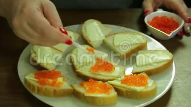 一个女人从一勺鱼子酱中取出红色的鱼子酱，用黄油涂在罐头上
